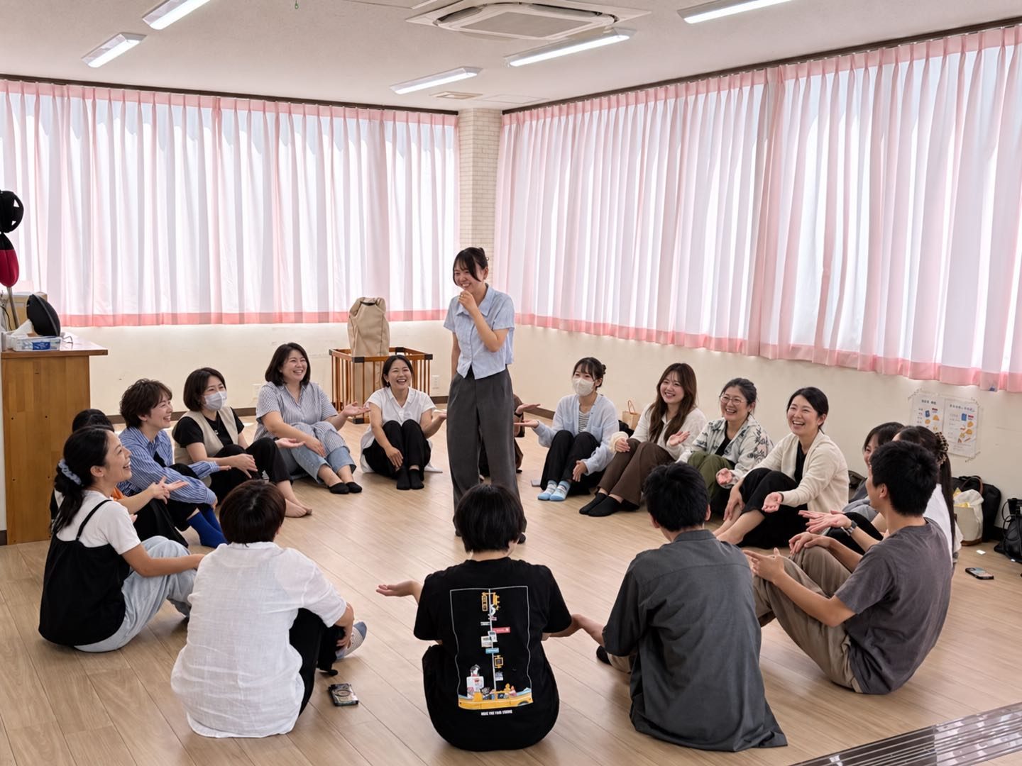 床に輪になって座り、笑顔で話し合うスタッフたち