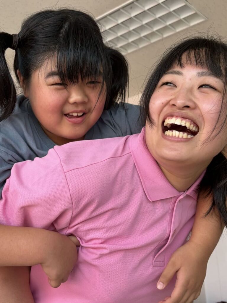 子どもと顔を寄せ合って大笑いするスタッフ