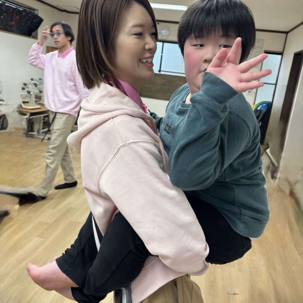 子どもを抱き上げて笑い合うスタッフ