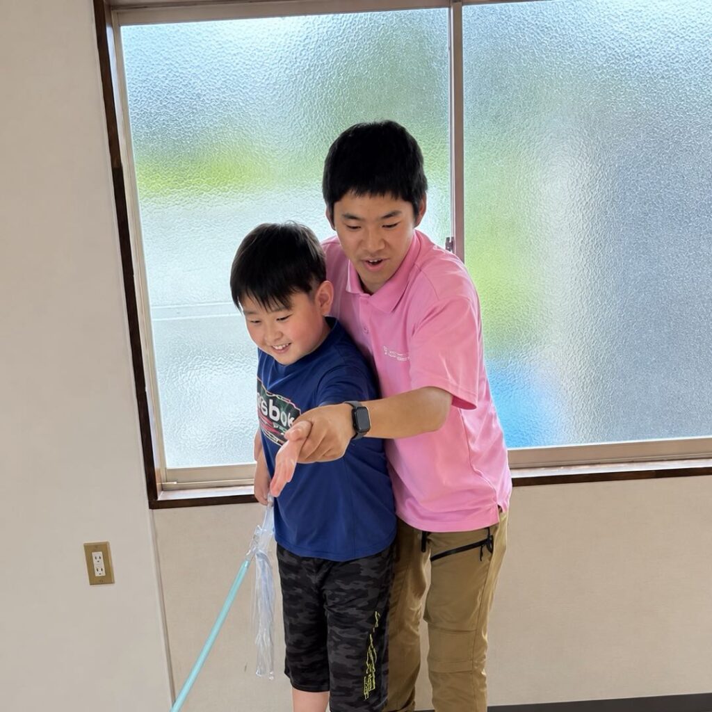 窓辺で子どもと肩を寄せ合う男性スタッフ