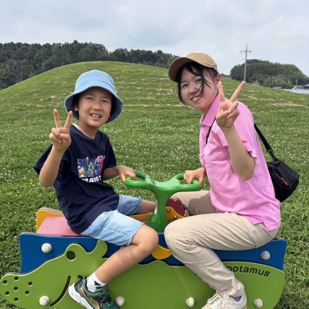 公園の遊具で、子どもと一緒にピースをするスタッフ