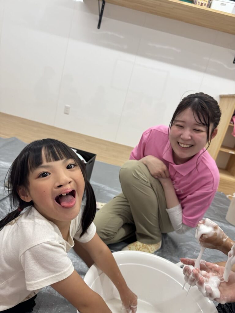 スライム遊びで、子どもと一緒に笑うスタッフ